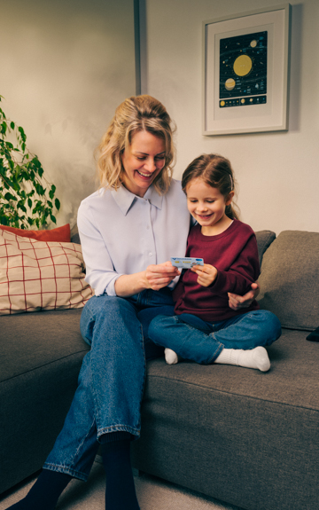 Mutter und Tochter sitzen auf der Couch und betrachten gemeinsam ein Buch.