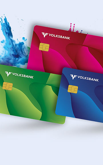 Eine junge Frau Mann mit blonden, kurzen Haaren hält lächelnd eine Debit Mastercard der Volksbank in der Hand.
