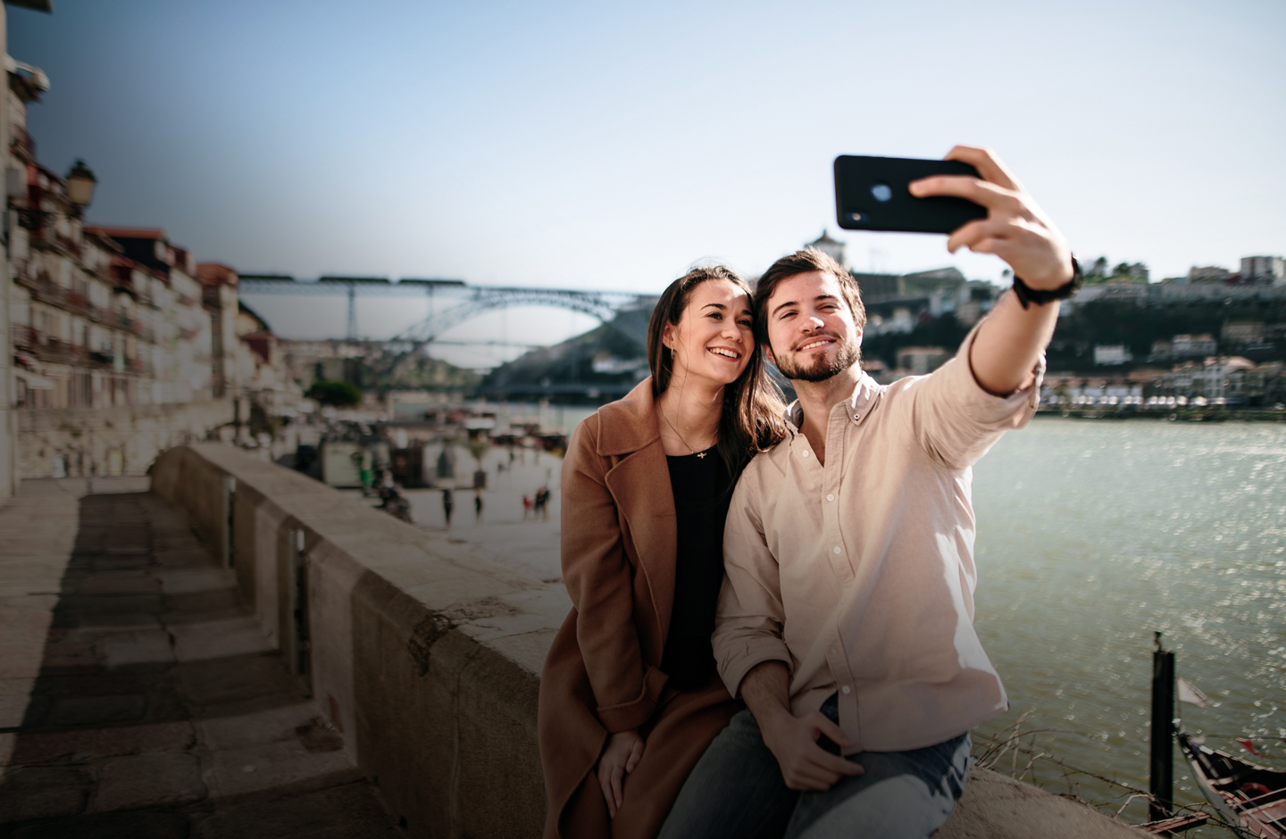 Eine Frau und ein Mann sitzen an einem Ufer und machen ein Selfie